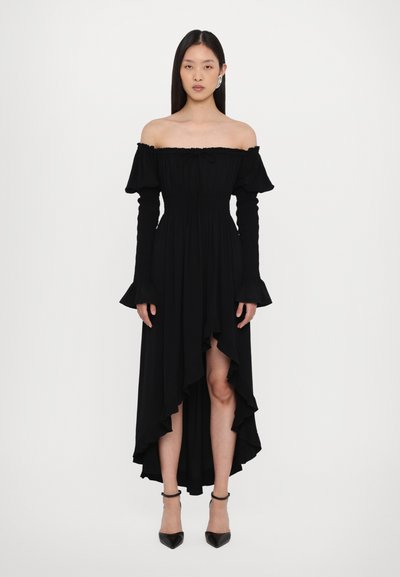 Schwarzes Off-Shoulder-Kleid mit gerafftem Oberteil, langen, enganliegenden Ärmeln und gerafftem High-Low-Saum. Gestylt mit schwarzen spitzen Absätzen.