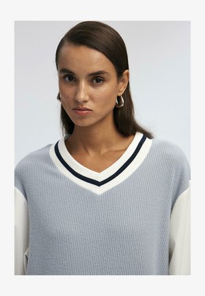 Svijetlosivi pleteni džemper s teksturiranim završetkom, s V-izrezom, bijelim i mornarsko plavim prugastim rubom, te dugim bijelim rukavima.
