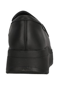 Svart lädersko som är lätt att ta på sig, med rundad bakdel, platt gummisula och synlig söm längs den övre kanten. Slät textur.