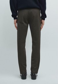 Mørkebrune, skræddersyede bukser med en glat tekstur, lige ben design og minimal detaljering, kombineret med sorte sko.