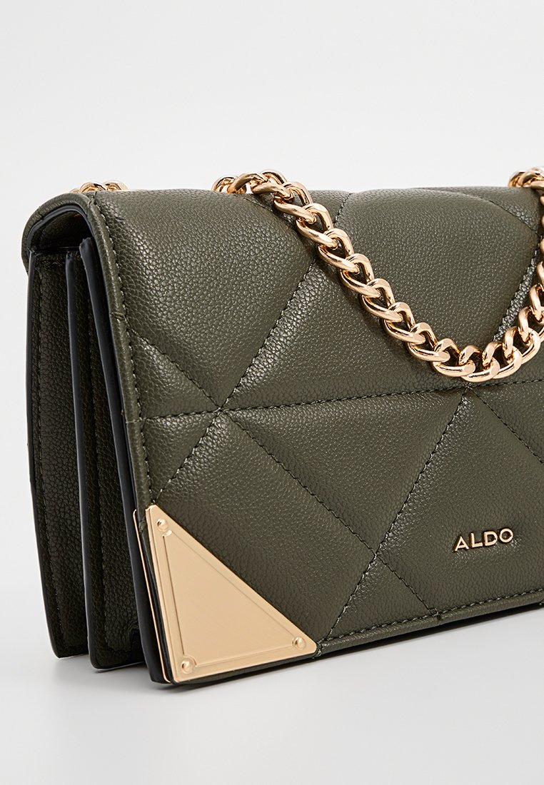 Sac à main en simili cuir matelassé vert olive avec une chaîne dorée et un accent triangulaire doré. Présente une forme structurée et une texture lisse.