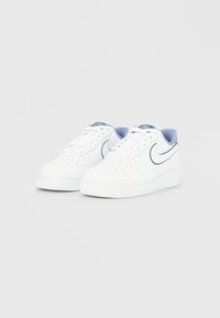 Fehér bőr tornacipő, sima textúrával, lekerekített orral, vastag fehér talppal, valamint világoskék kiemeléssel a saroknál és a nyelvnél.