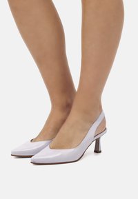 Tacchi slingback di colore viola chiaro con punta affusolata, tacco sottile e texture in pelle liscia. Sides aperti e design a scollatura bassa per ventilazione.