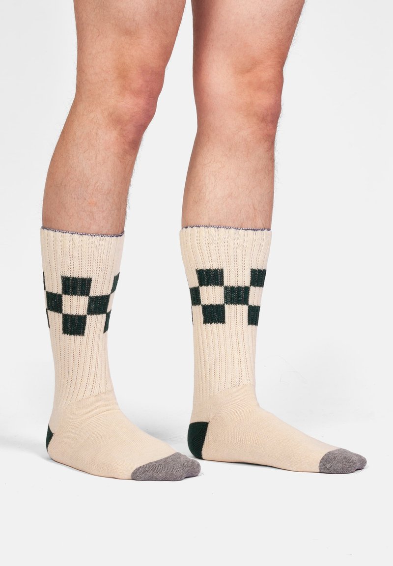 Calze beige alte fino al ginocchio con motivi a scacchi verdi. Tessuto a coste con punta e tallone rinforzati in grigio.