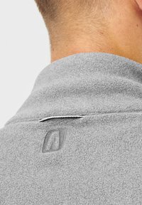 Szary polarowy jacket widok z tyłu z wysokim kołnierzem, posiadający teksturowany materiał i małe wyszywane logo w pobliżu szyi.