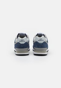 Sneaker in suede blu con accenti bianchi e grigi, dotate di un colletto imbottito e di una suola nera robusta. Logo del marchio sul tallone e sulla linguetta.