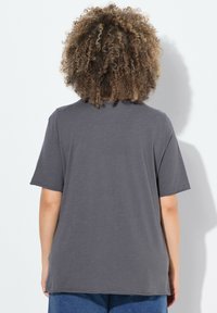 Šedé tričko s krátkým rukávem a uvolněným střihem, vyrobené z měkké látky. Jednoduchý design s kulatým výstřihem, bez viditelných vzorů nebo akcentů.