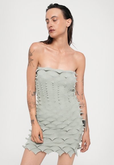 Vestido sin tirantes en verde claro con un diseño texturizado y en capas. Presenta bordes ondulados y una silueta ajustada, hecho de un tejido elástico.