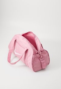 Rózsaszín nejlon tornazsák fehér Nike logóval, elülső zippzáros zsebbel, állítható vállpánttal és tágas belső térrel.