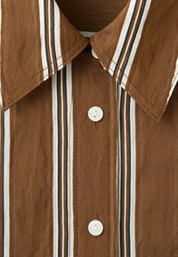 Camisa marrón con rayas verticales blancas, negras y beige, con cuello puntiagudo y botones blancos en la parte delantera.