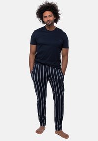 Marinblå T-shirt med bröstficka som matchas med marinblå och vita randiga pyjamasbyxor. Mjuk tygkvalitet, avslappnad passform och ankel-längd design.