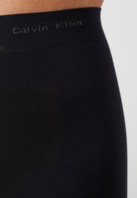 Svarta Calvin Klein leggings med en mjuk, ribbad struktur och en midja där varumärket subtilt är vävt i grått.