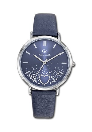 Cadran de montre rond bleu avec des index argentés, des aiguilles argentées et un motif de cœur en cristal au-dessus d'un bracelet en cuir bleu.