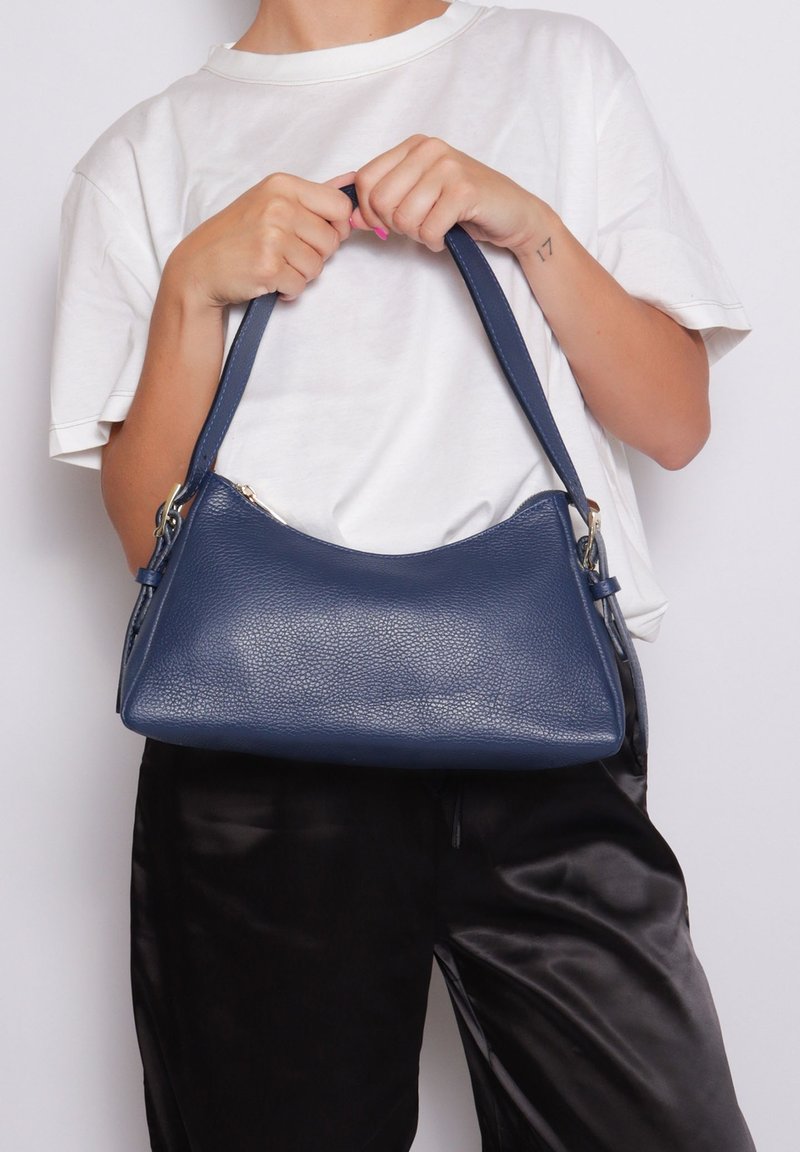 Marineblauwe leren schoudertas met een gestructureerd oppervlak, een halvemaanvorm en één schouderband; beschikt over een ritssluiting en metalen hardware-accenten.
