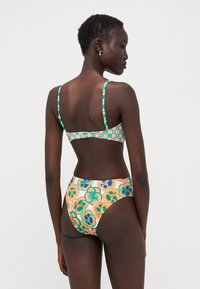 Bikini multicolore avec un motif floral, des bretelles réglables et une fermeture à clip. Le bas taille haute a une texture lisse.