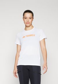 Hvit kortermet trenings-T-skjorte med en oransje "TERREX"-logo på forsiden. Glatt, lett stoff med avslappet passform.
