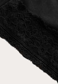 Svart tyg med dekorativ spetskant som har blommönster och scalloped edge. Mjuk textur med intrikata detaljer längs fållen.
