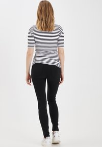 Pruhovaný černob�ílý top s krátkým rukávem, doplněný černými slim-fit džíny. Obuv tvoří bílé tenisky. Jednoduchý design, moderní střih.
