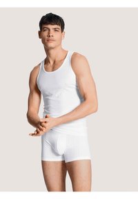 Witte tanktop en bijpassende boxershorts van ribstof. Het ontwerp is aansluitend, met een zachte textuur en subtiele naden.