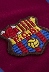 Geborduurd FC Barcelona-logo met kastanjebruine, blauwe en gele secties, met een voetbalontwerp en een bruine rand op textuurstof.