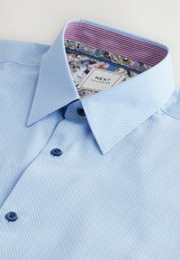 Himmelblaues gemustertes Hemd mit strukturiertem Oberflächenmaterial, strukturiertem Kragen, dunklen Knöpfen und einem bunten Blumen-Innenfutter.