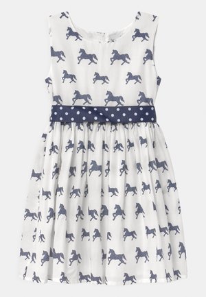 Weißes ärmelloses Kleid mit einem dunkelblauen Polka-Dot-Gürtel und gleichmäßig verteilten dunkelblauen Pferdemustern auf dem Stoff.