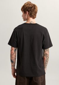 Black cotton T-shirt with a relaxed fit, crew neckline, and short sleeves. Features a solid color and a smooth texture.