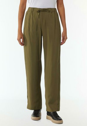 Olivegrüne, leichte Hose mit elastischem Bund und Kordelzug, gerade geschnitten und mit seitlichen Taschen, kombiniert mit schwarzen Sneakers.