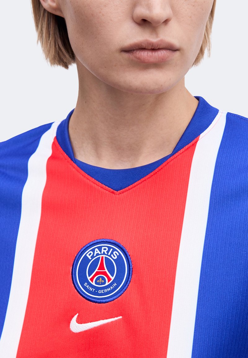 Gros plan d’un torse portant un maillot de football du Paris Saint-Germain avec des rayures verticales bleu, rouge et blanc et le logo Nike.