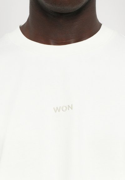 Λευκό βαμβακερό μπλουζάκι με στρογγυλή λαιμόκοψη και κεντημένο "WON" σε ανοιχτό γκρι στην αριστερή πλευρά του στήθους. Λείος υφασμάτινος χαρακτήρας.