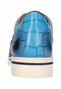 Zapatilla azul con un acabado texturizado y brillante, que presenta un panel lateral tejido y suela de goma blanca con una franja azul.