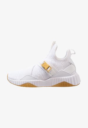 Witte instapsneaker met gestructureerde gebreide stof, een gouden gespsluiting en een gestructureerde witte zool met een doorschijnende gumzool.