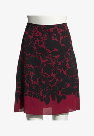 Jupe rouge longueur genou avec motif floral noir exposée sur un buste de mannequin blanc.