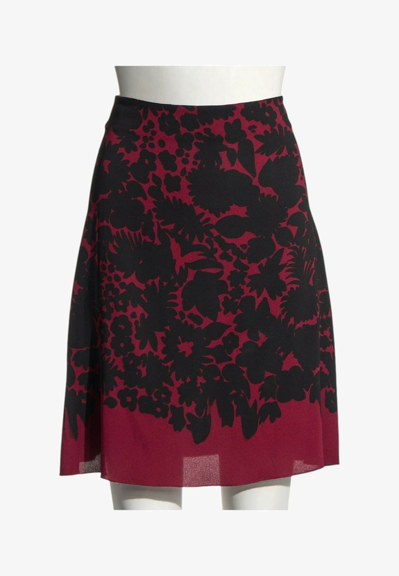 Jupe rouge longueur genou avec motif floral noir exposée sur un buste de mannequin blanc.