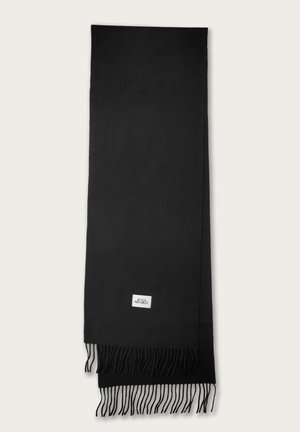 Écharpe noire en tissu doux, avec des bords à franges. Une petite étiquette blanche avec du texte est visible près du bas.