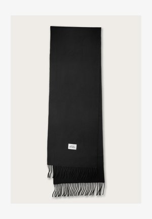 Zwarte sjaal van zacht materiaal, met franjes aan de randen. Een klein wit label met tekst is zichtbaar nabij de onderkant.