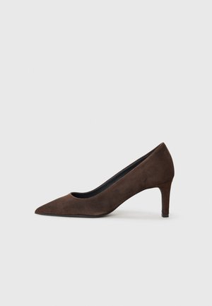 Sapato pump de salto alto em camurça castanha, com bico fino e salto estreito e afinado. Textura suave com um design minimalista e sem ferros visíveis.