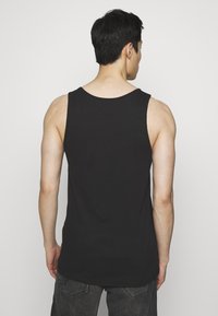 Canotta nera senza maniche in cotone, con scollo rotondo e design aderente, caratterizzata da una texture liscia e priva di motivi visibili.