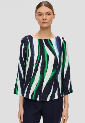 Mehrfarbiges Oberteil mit grünen, blauen, schwarzen und weißen Streifen. Design mit Boot-Ausschnitt und dreiviertel Ärmeln. Leichte Stofftextur.