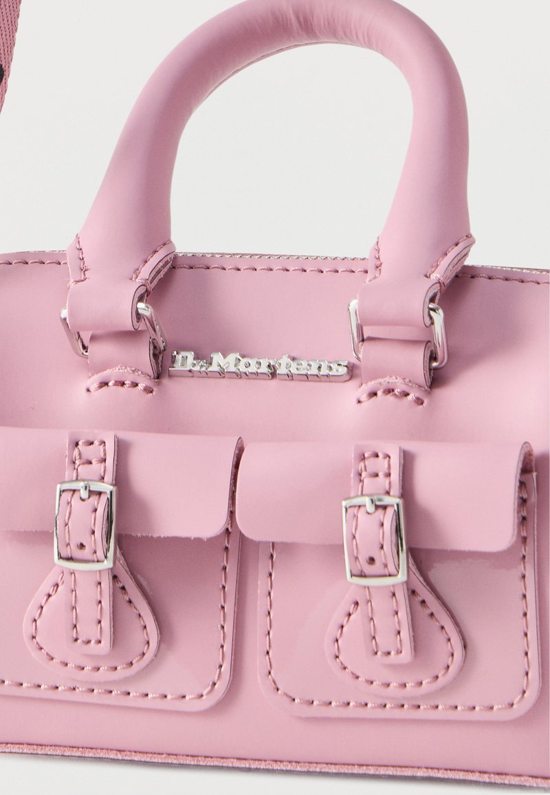 Borsa a mano in pelle rosa con fibbie argentate e doppi manici, dotata di due tasche frontali e targhetta con il logo "Dr. Martens".