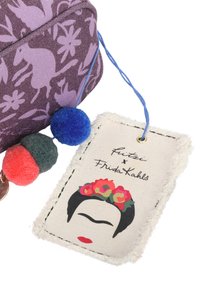 Lila Stofftasche mit floralem Muster, drei bunten Pom-Poms und einem Etikett mit einem Blumenkranzdesign und dem Text "Futzi x Frida Kahlo."