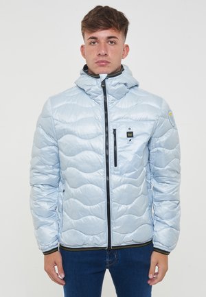 Giacca puffer azzurro chiaro con motivo a onde trapuntato, chiusura con zip, tasche frontali e cappuccio. Dettagli neri sulla zip e sui polsini.