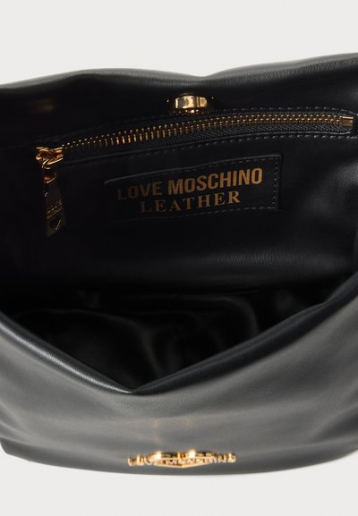 Интериор на черна кожена чанта с метален цип и етикет с надпис "Love Moschino Leather."