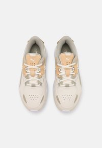 Baskets beige et gris clair avec une tige en cuir texturé, des accents en mesh, des panneaux perforés et une semelle en caoutchouc blanche. Design à lacets avec détail du logo.