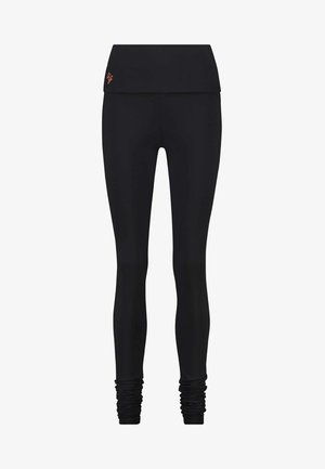 Black leggings featuring a wide waistband, stretchy material, and gathered ankle details. Smooth texture with subtle logo on waistband.