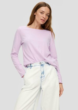 Chemisier long à manches longues de couleur violet clair avec un col rond, associé à un jean blanc taille haute présentant un motif tie-dye bleu clair.