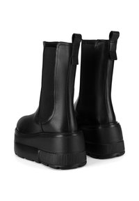 Czarne skórzane botki na kostkę z elastycznymi panelami bocznymi, masywną podeszwą na platformie oraz teksturowanymi akcentami u podstawy i pętelkami z tyłu.