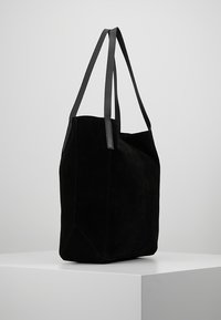 Czarna zamszowa torba tote z dwiema płaskimi pasekami na ramię, kanciastym kształtem i przeszywanymi detalami. Gładka faktura i minimalistyczny design.