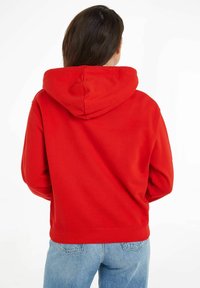 Sweatshirt à capuche rouge avec une coupe décontractée, fabriqué à partir d'un tissu doux. Présente une grande capuche et des poignets côtelés aux manches et à l'ourlet.