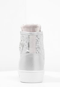 Stříbrné vysoké tenisky s texturovaným flitrovým svrškem, hladkými kovovými akcenty a polstrovaným límcem. Na boku se nachází logo.